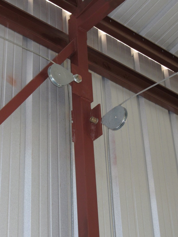Interior commercial hanger utilizes fixed eye pulley blocks for easy opening of heavy duty hanger doors