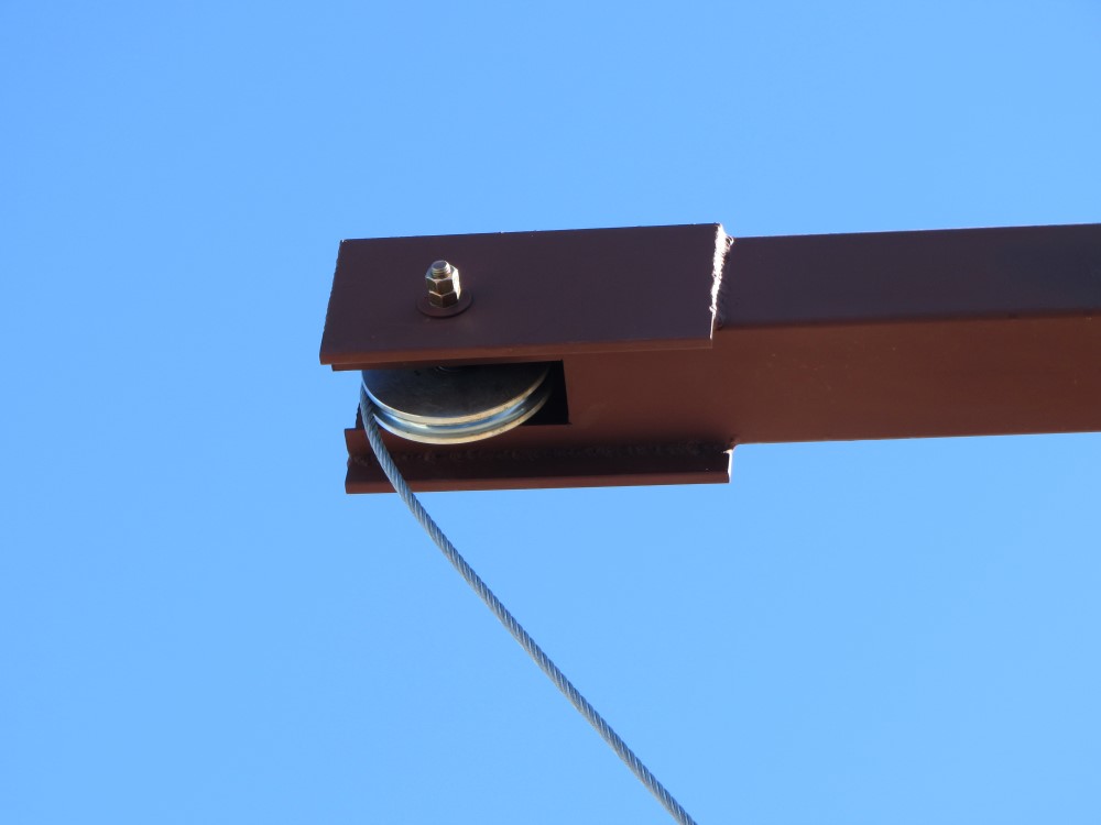 Close-up view of exterior cable pulley sheave used in commercial overhead door